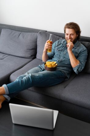 full-shot-man-sitting-couch-with-drink-freepik