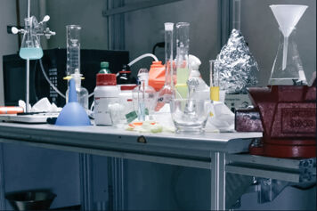 Vials and beakers of unknown liquid substances in a lab.